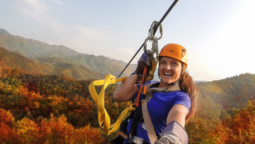 a woman zip lines across a background of fall colored mountains