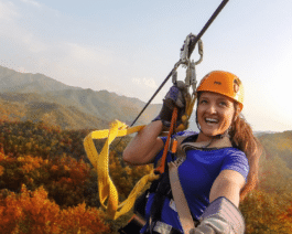 a woman zip lines across a background of fall colored mountains