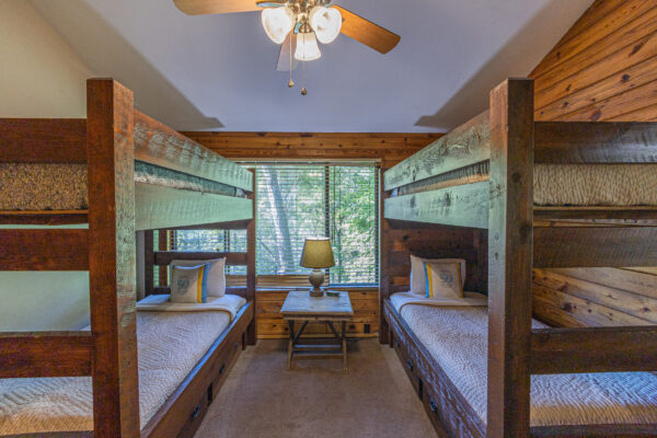 cabin bedroom with two bunkbeds, table and window