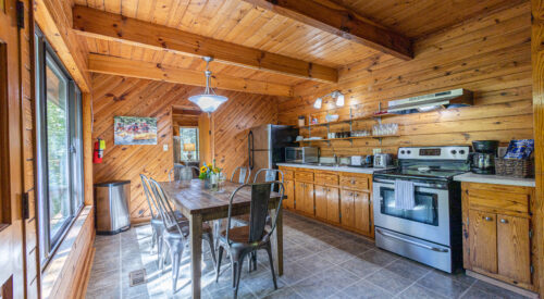 cabin kitchen with long dining table, oven and cabinets