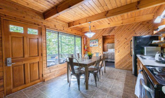 cabin dining area with long table and large window view out into forest