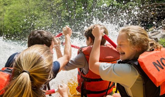 Girls getting splashed while white water rafting north carolina.