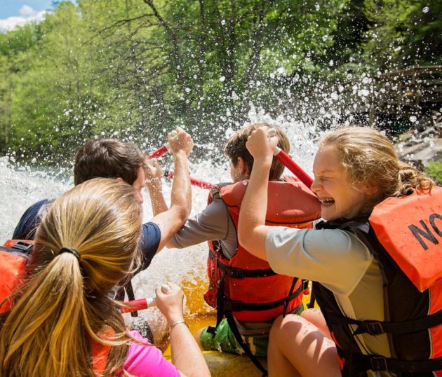 Girls getting splashed while white water rafting north carolina.