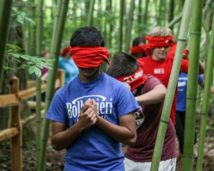 Teen blindfold walking during a team building activity outdoors