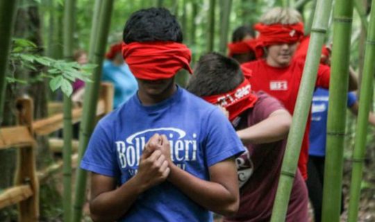 Teen blindfold walking during a team building activity outdoors