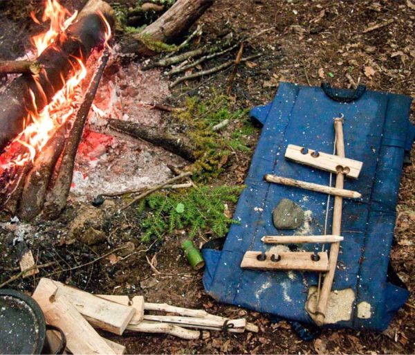 Wood that was used to start a fire laying next to a campfire