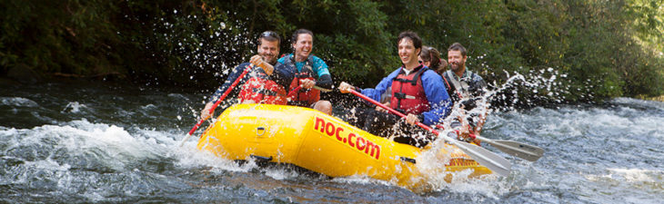 Group of guests rafting through whitewater