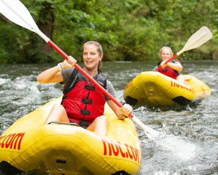 Women paddling in whitewater on duckies