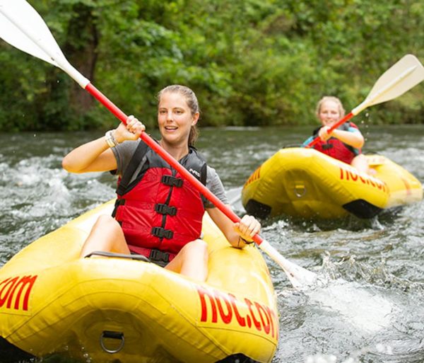 Women paddling in whitewater on duckies