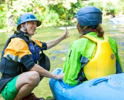 Student learning how to whitewater kayak from an instructor