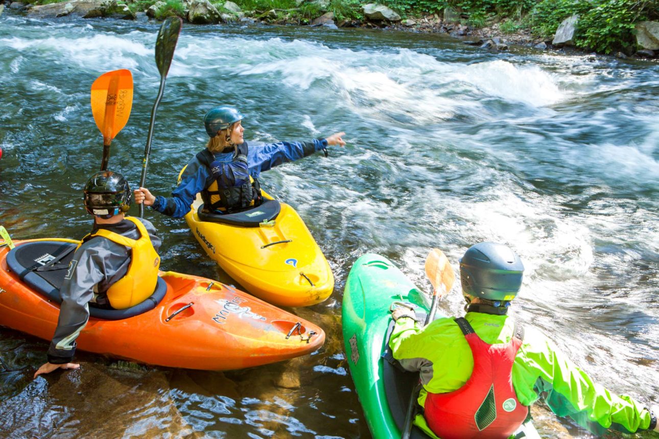 NOC guests kayaking a river in paddling school