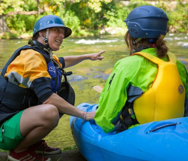 Student learning how to whitewater kayak from an instructor