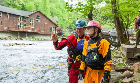 Instructors and students scouting a rapid during swiftwater rescue course