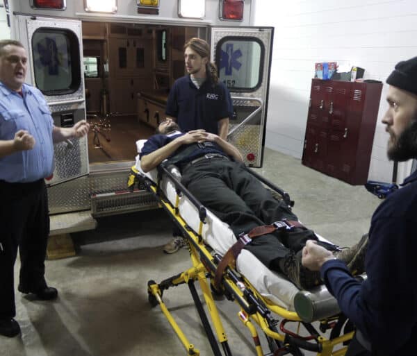 emt students escort a patient into an ambulance
