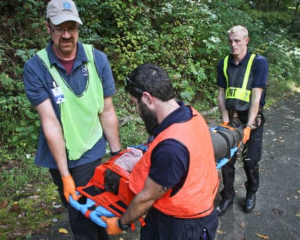 Three people carrying a person in a stretcher