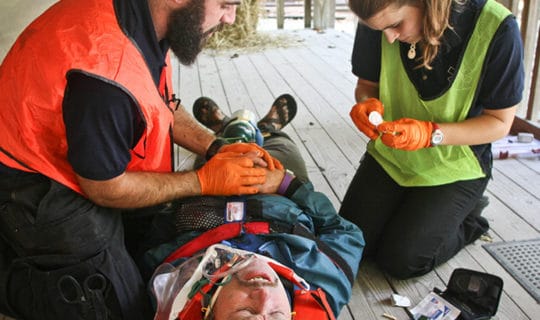 Two people tending to a person in a stretcher