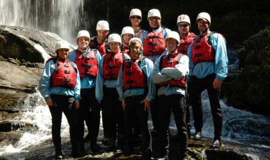 paddlers wearing helmets, life jackets, and wetsuits