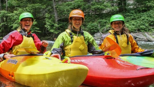 Three women kayaking and smiling