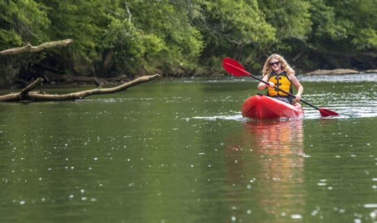 A woman paddles a red kayak down the Chattahoochee River