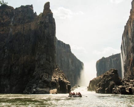 Rafters traveling through a cliff-lined river.