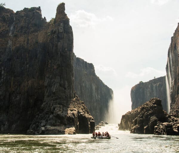 Rafters traveling through a cliff-lined river.