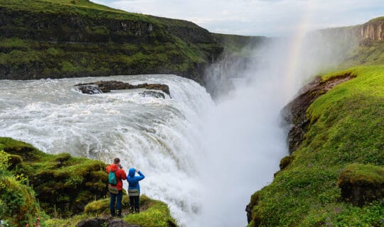 Hikers viewing waterfall and rainbow.