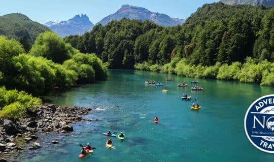 kakayers and rafters paddle the blue waters of the futaleufu river amongst towering green mountains