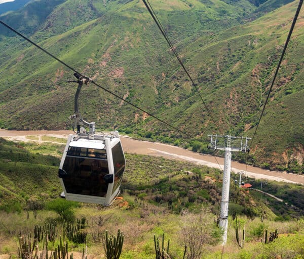 a gondola travels down the mountain overlooking mountain ranges and a winding river