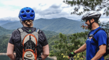 two mountain bikers look out over fontana lake with mountains in the background
