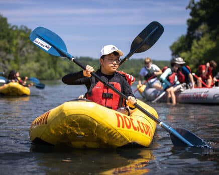 Teen in an inflatable ducky paddling around during Summer Camp.