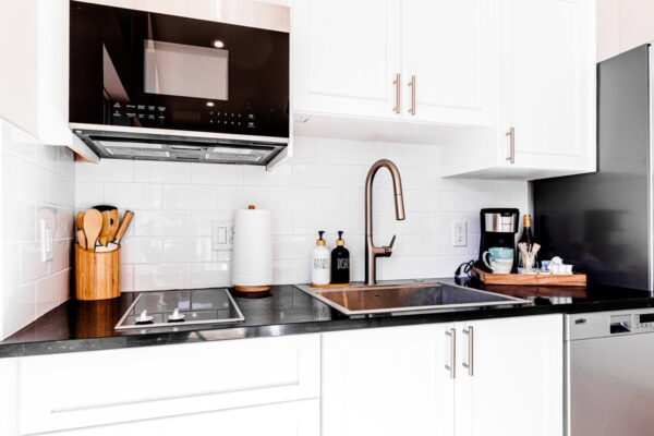 White cabinets in a kitchen with a coffee maker, microwave and stovetop.
