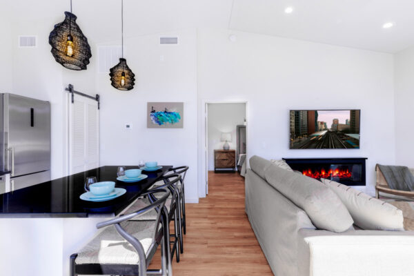 wide view entry of sitting area with couch and eat in kitchen with bar counter and stools facing bedroom.