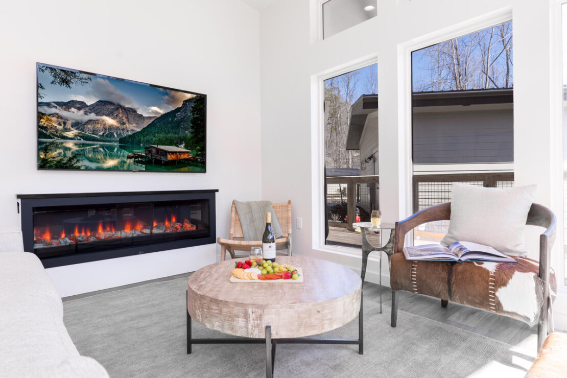 sitting area with electric fireplace, coffee table with charcuterie board and chairs.