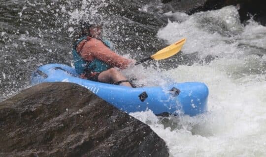 A person going down a small rapid in a packraft.