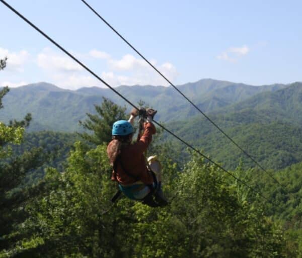 Image of a girl going down a zipline with the beautiful Nantahala National Forest in the background.