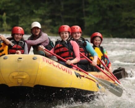 young adults in a yellow raft in a river