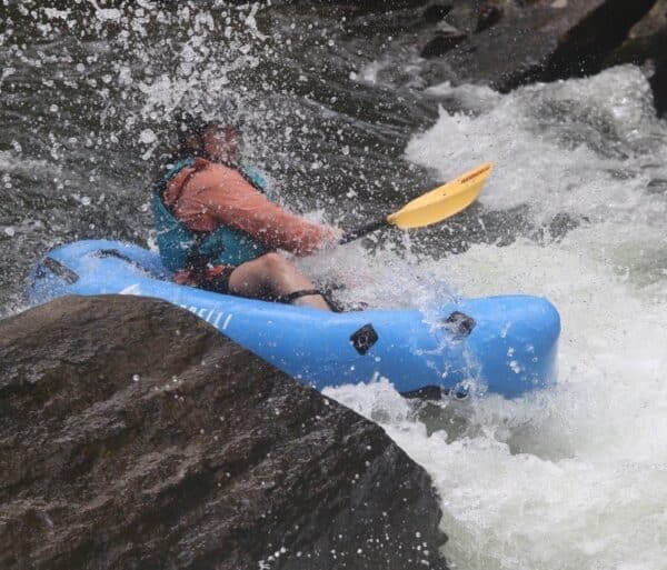 blue packraft splashing through a rapic