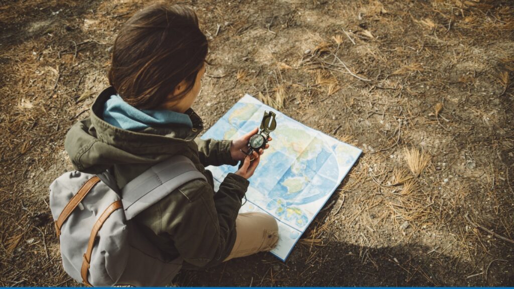 Woman reading a map while utilizing a compass.