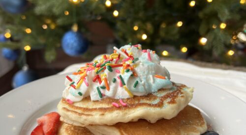four stack of pancakes with strawberries and sprinkles