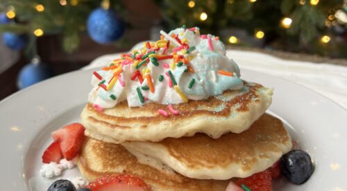 four stack of pancakes with strawberries and sprinkles