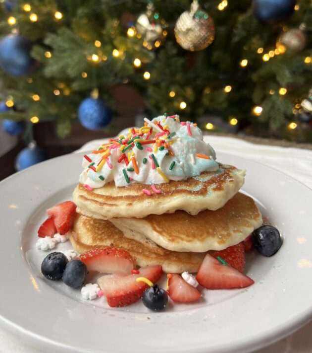 four stack of pancakes with strawberries and sprinkles