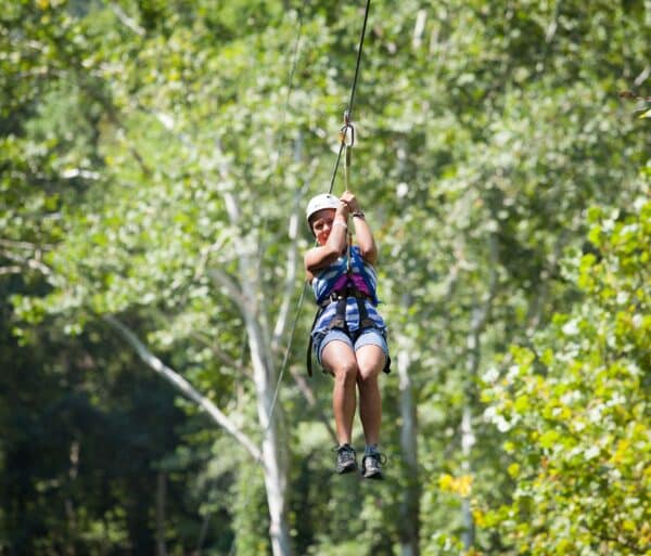 child zip lining through tree canopies