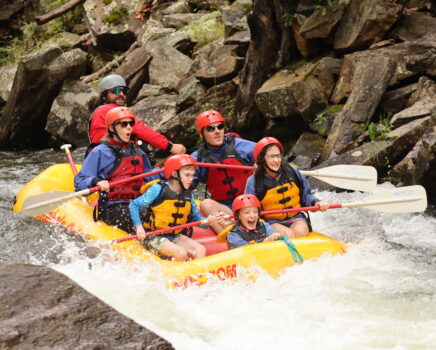 A group of guests splashes down the Nantahala River in a yellow guided raft.