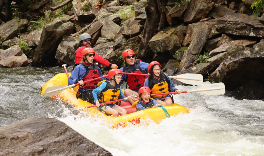 A group of guests splashes down the Nantahala River in a yellow guided raft.