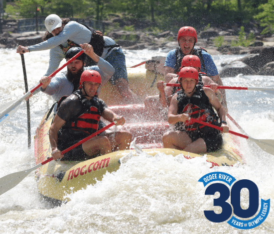 Group rafting through rapids on the Ocoee River Olympic section with NOC guide and 30 year legacy logo