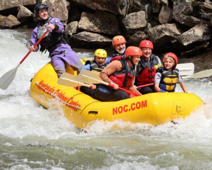 A family splashes down the French Broad River in a guided NOC raft.