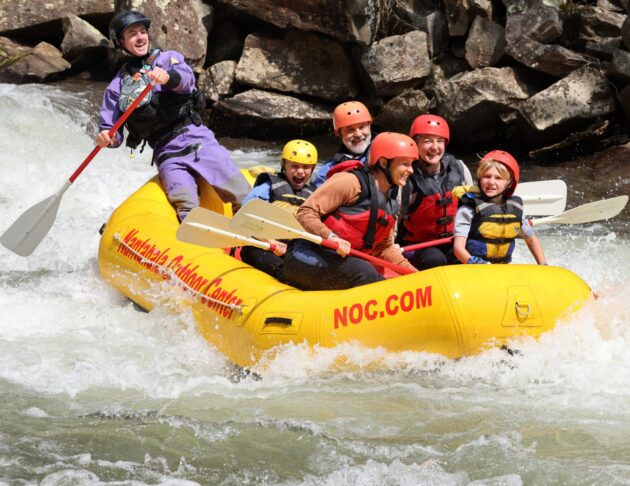 A family splashes down the French Broad River in a guided NOC raft.