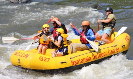 A family splashes down the French Broad River in an NOC guided raft.